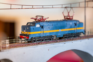 Vintage blue and yellow electric locomotive model crossing bridge