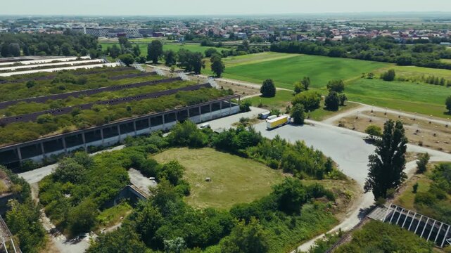 aerial - overgrown industrial ruins near Zagreb Croatia beside fields and scattered vehicles