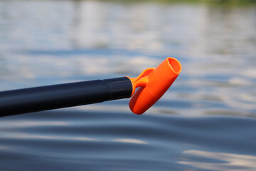 Stand-up paddleboard handle, close-up. Active way of summer recreation. Active summer vacation. Water sports. Light plastic paddle on the background of water, river