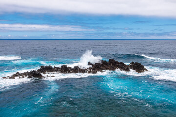 The rough Atlantic Ocean and the volcanic rocks of Porto Moniz. Madeira. Portugal. Waves crashing on the rocks.