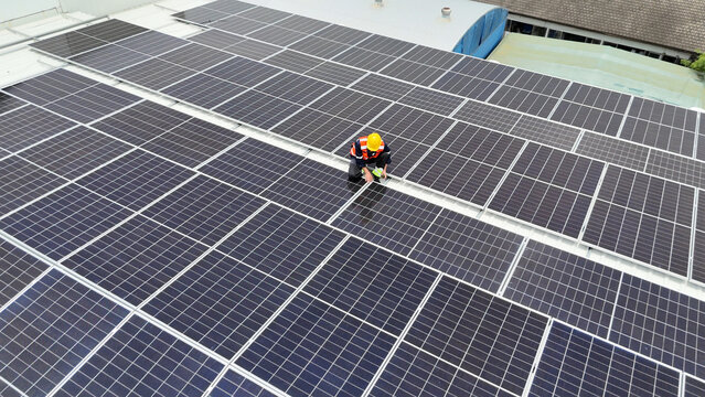 Worker conducts maintenance on solar panels atop a commercial building during midday