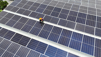 Worker performs maintenance on solar panels in a clean energy installation during daytime