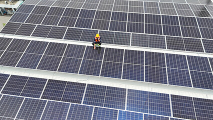 Solar panel installation in progress on a rooftop by a worker wearing safety gear
