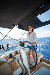 Young woman steering a sailing yacht near Croatia, confidently standing at the helm. Female leadership, empowerment and freedom in maritime lifestyle.