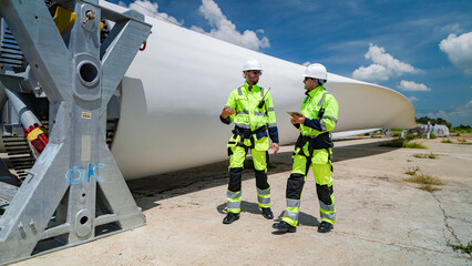 Technicians discussing wind turbine assembly at a construction site in sunny weather