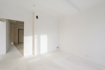 bright, empty room with white walls, floor, and a doorway leading to another space. It appears to be under renovation or freshly painted
