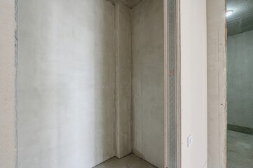 An interior shot of a room under construction, showcasing unfinished walls, plaster, and a doorway...