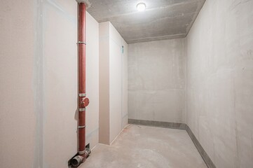 bare room with unfinished walls, concrete floor and ceiling, and a red pipe running vertically