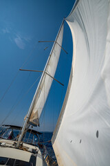 Fototapeta premium White sails filled with wind, seen from the bow of a sailing yacht near Croatia. Freedom, clean energy, adventure and mindful travel on the open sea.
