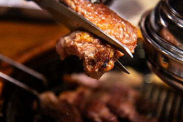 cutting the roasted pork with the scissors on the charcoal grill