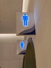 A pair of glowing blue restroom signs for male and female toilets, mounted above separate entrances...