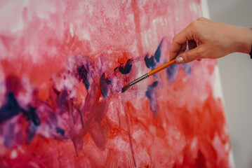 Artist painting abstract artwork with brush and red and purple colors