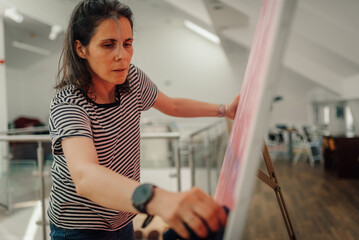 Female artist cleaning painting in art gallery or studio