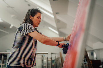 Artist cleaning large abstract painting in studio