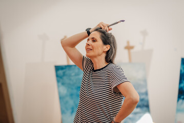 Female artist contemplating her next stroke in art studio