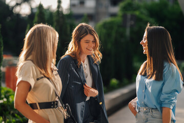 Three young businesswomen talking and smiling outdoors