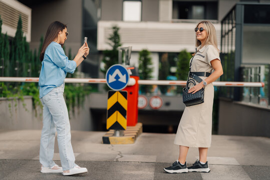 Influencer posing while friend is taking photos with smartphone in urban setting - Powered by Adobe