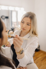 Professional makeup artist applying foundation on client's face in beauty salon