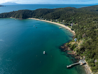 Aerial view of boats moored in the turquoise waters of a bay in Kawau Island, New Zealand. Lush...
