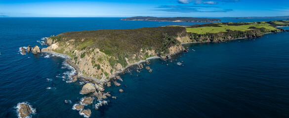 Aerial view of a rocky coastline meeting the ocean in Tawharanui, New Zealand. The landscape...