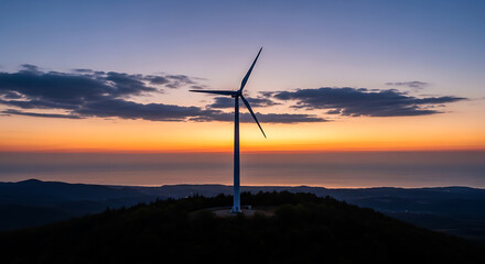 Obraz premium Wind turbine generating sustainable energy at dawn over mountains and ocean horizon