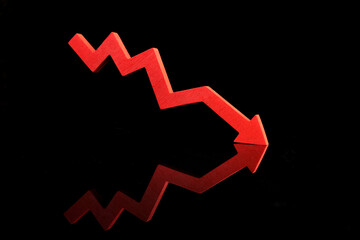 A red zigzag arrow with a downward trend reflects on a black surface, symbolizing financial...