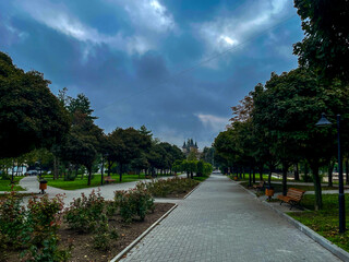 Scenic park alley with historic building under cloudy sky