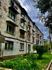 Old residential building with overgrown yard and hanging laundry