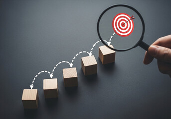 Photo of magnifying glass focusing on a target with an arrow hitting the bullseye showing a business strategy