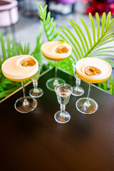 Elegant cocktail glasses with yellow passion fruit drinks, garnished with halved fruit, arranged on...