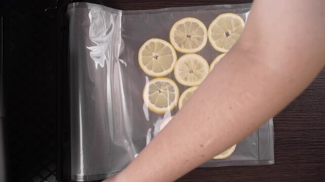 Vacuum lemon slices packaging for long-term storage. vacuum sealer. Woman packing citrus fruits and Vacuuming food in the kitchen