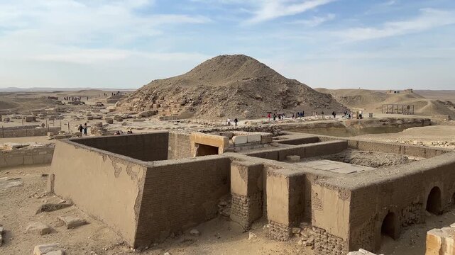 Saqqara, Egypt - Feb 5, 2024: Ancient Egyptian mastaba tomb in Saqqara Necropolis with the Pyramid of Unas visible in the background.