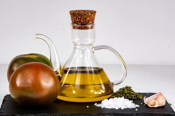 tomate negro cortado por la mitad con una jarrita de cristal con aceite de oliva y otro con sal gruesa 