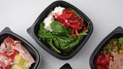 A vibrant collection of fresh and nutritious meal prep salads is neatly arranged in sleek black containers, perfect for a healthy daily diet.