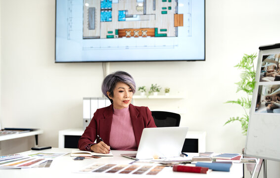 Professional senior interior designers or architects working  in office,  using a laptop and considering material samples.