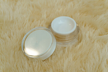 an opened cream jar stands on a yellow fur