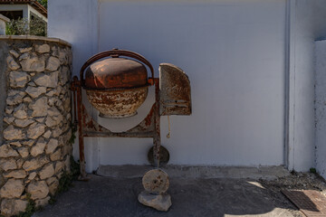 An old, rusty concrete mixer sits outside the garage door Croatia Ciovo