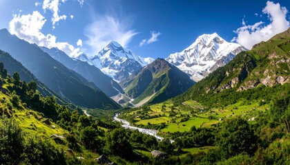 Panoramic view of snow-capped mountains, green valley, and clear blue sky landscape