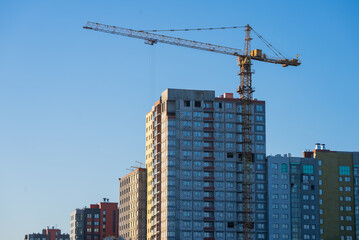 Construction crane building new residential apartment building under clear blue sky, representing...