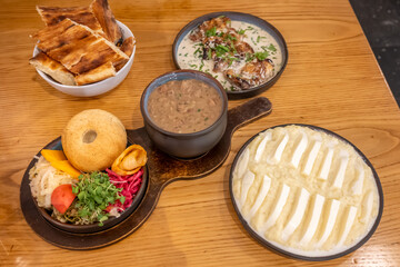 A traditional Georgian feast including Ghomi with Cheese, Shkmeruli (creamy garlic chicken), Puri (bread), Lobio (bean stew) with pickled vegetables (jonjoli and cabbage) and Mchadi (corn bread)