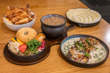A traditional Georgian feast including Ghomi with Cheese, Shkmeruli (creamy garlic chicken), Puri (bread), Lobio (bean stew) with pickled vegetables (jonjoli and cabbage) and Mchadi (corn bread)