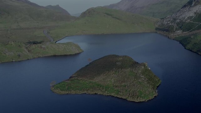 Drone flyover of the island in Llyn y Dywarchen lake, North Wales. Also called Turf Island or Floating Island, this rural landscape is linked to Tylwyth Teg Welsh folklore and ancient legends.