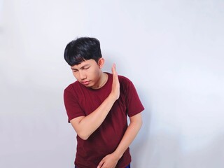 A young Asian man in a maroon shirt raises his hand, gesturing stop with a serious expression on a...