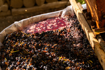 Traditional winemaking process showcasing crushed grapes in a wooden fermentation vat, surrounded...