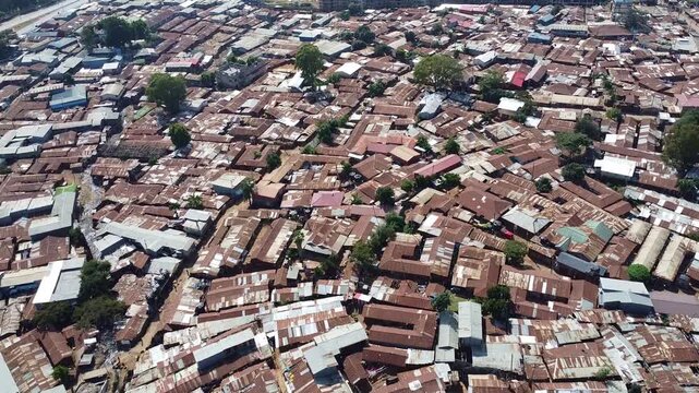 An aerial view of a densely packed slum with rusty tin roofs and narrow pathways