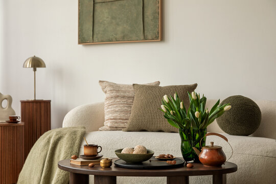 Close-up of cozy spring interior with tulips, ceramic teapot and decorative tray on a dark wooden coffee table.