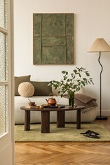 Earth-toned interior with mock up wall art, soft white sofa, green glass vase with flowers and cozy...
