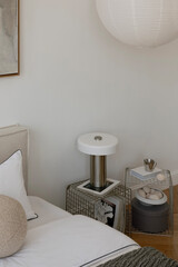 Modern nightstand styling with a sculptural lamp, wire frame tables and minimal ceramic decor in soft, neutral tones.