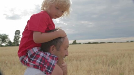 Close-Up of Grandchild on Grandfather’s Shoulders in Wheatfield