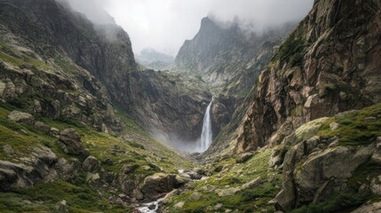 Verdant mountain pass with a thin waterfall cascading down shadowed rocks